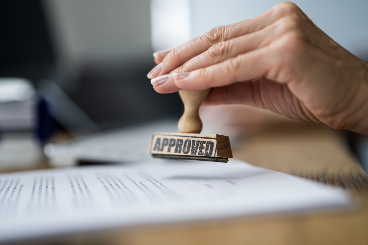 An advisor using an “approved” stamp on a study permit document