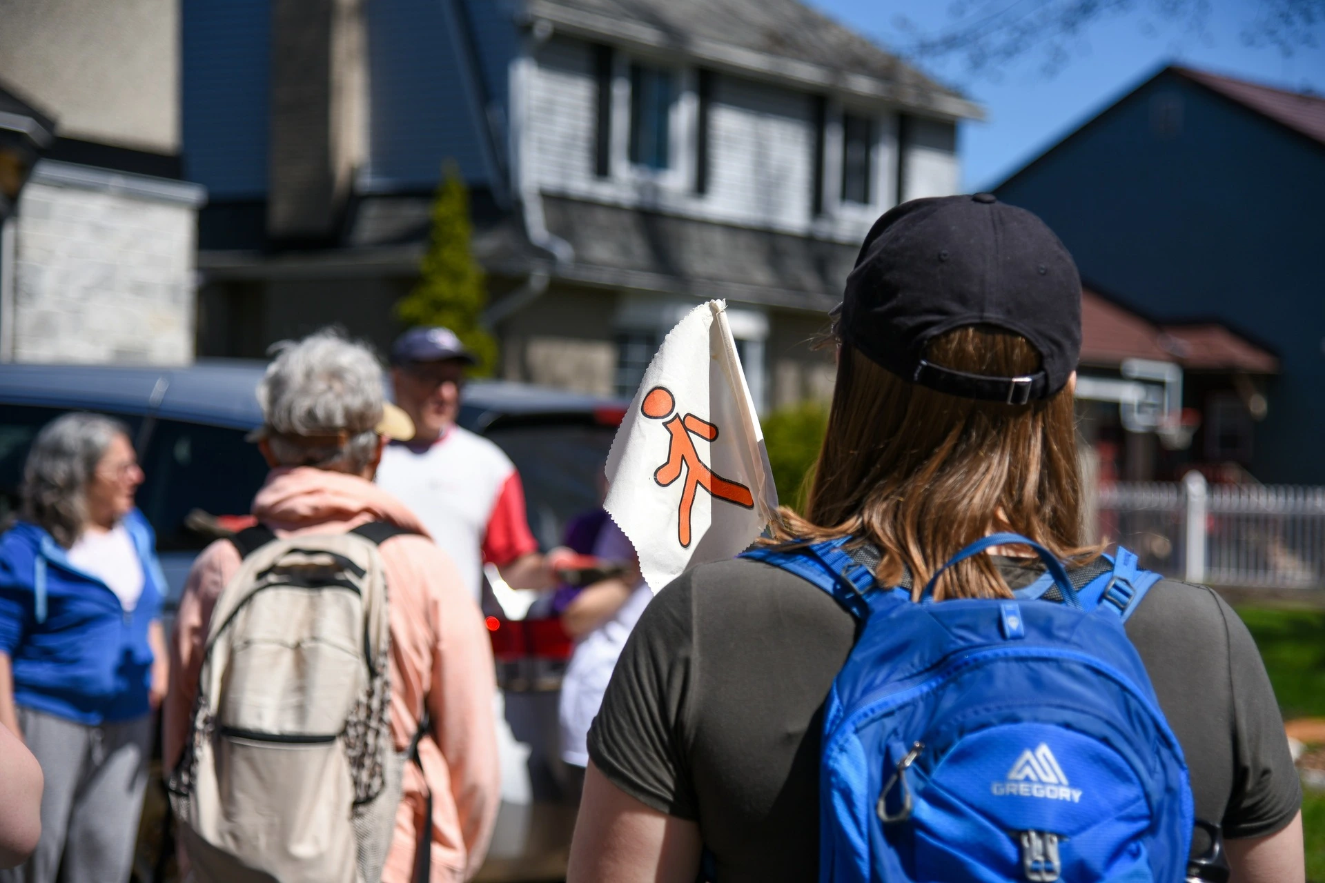 A group of people walking on the street with backpacks on a walking tour. 